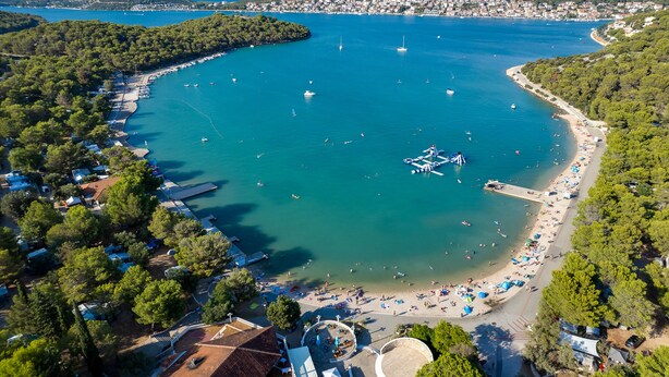 Vista aérea de una zona costera con playa, barcos y un puerto deportivo.