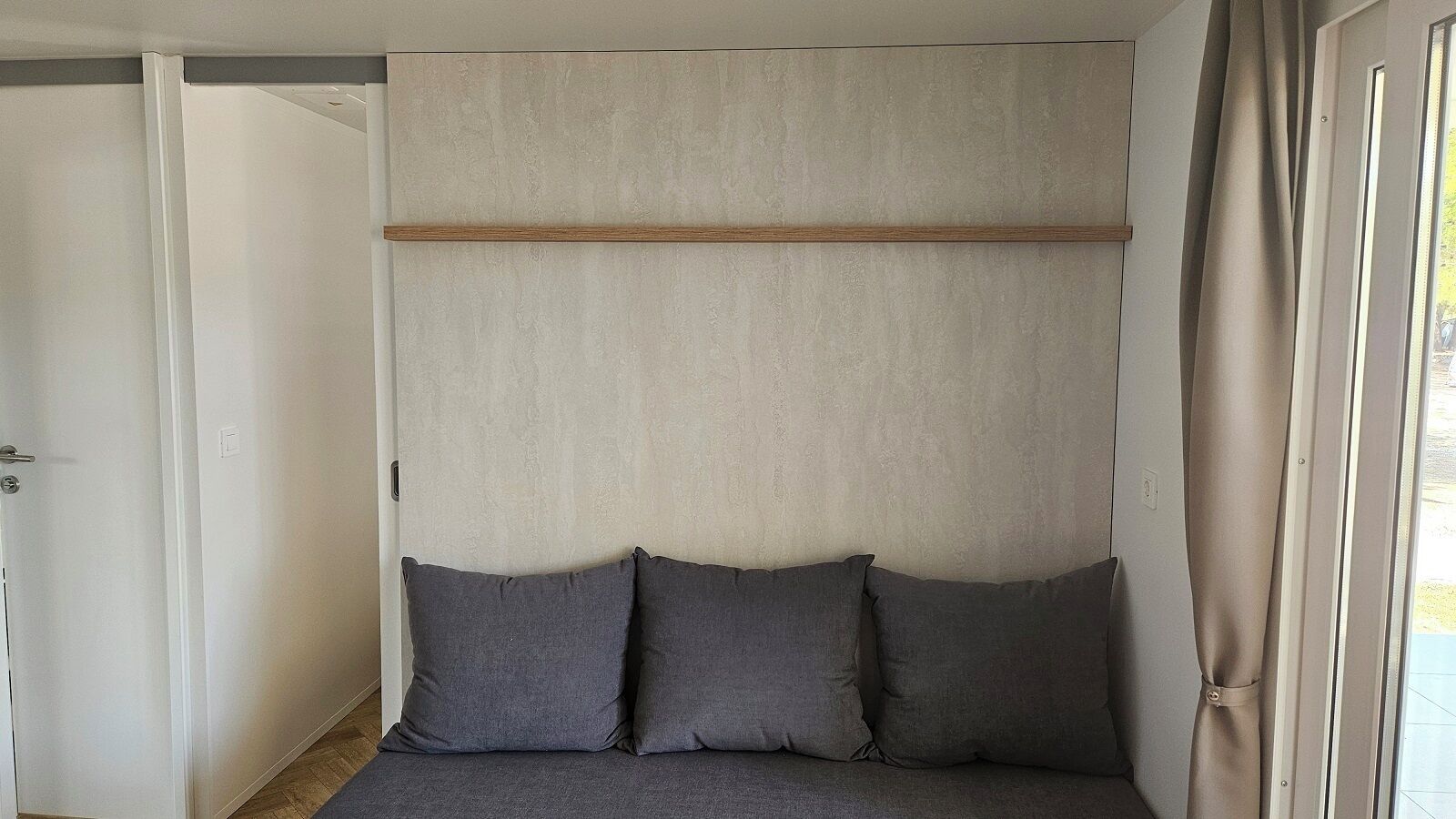 Una stanza con un letto, una porta e una finestra con tende.