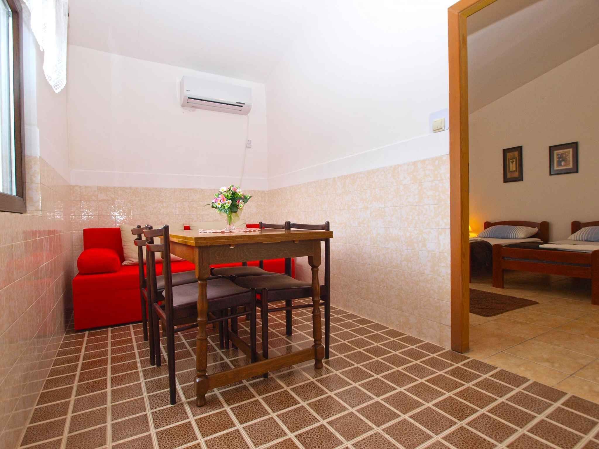 A compact living space with a dining area, a red sofa, a wooden table, and a small kitchenette.