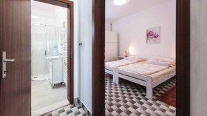 A bedroom with a checkered floor, a bed, a nightstand, and a wall-mounted lamp. - Holiday apartment near the beach (Pješćana Uvala)