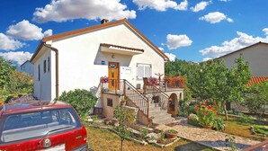 A two-story house with a white exterior and a red car parked in front. - Holiday apartment near the beach (Pješćana Uvala)