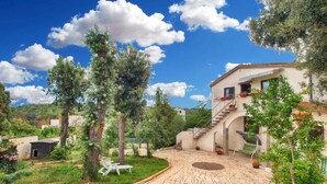A courtyard with a stone pathway leading to a building with a staircase and a pool area.