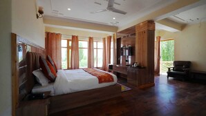 A spacious bedroom with a large bed, wooden furniture, a TV, and a balcony with a chair. - Hotel Martsemik (Leh)