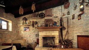 Ein rustikales Interieur mit Steinwand, Kamin, Holzmöbeln und verschiedenen Dekorationen.