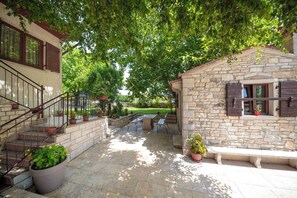 A stone building with a stone staircase, a patio with a table and chairs, and potted plants. - Holiday apartment with air conditioning (Matohanci)