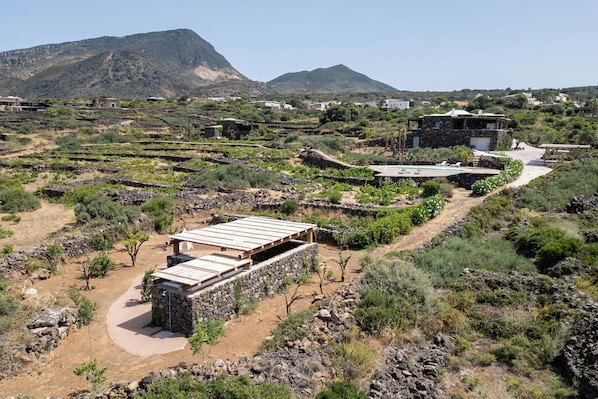 A rural landscape with stone buildings, terraced fields, and a clear sky.