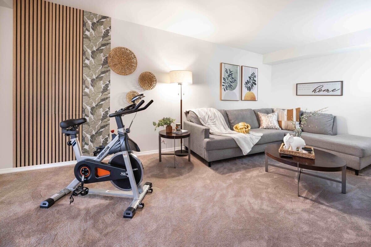 A living room with a stationary bike, grey sofa, coffee table, and decorative items.