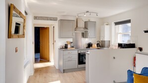 A modern kitchen with grey cabinets, a stainless steel range hood, and a built-in oven. - Little Edge: Bright and Modern Central Apartment (Berwick-upon-Tweed)