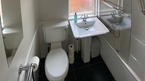A small, clean bathroom with a toilet, sink, and shower.