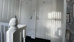 A hallway with two white doors, numbered 2 and 3, and a white column with a balustrade.