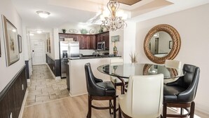 A modern kitchen with dark wood cabinets, a central island, and a dining area with a glass table and leather chairs. - Coastal Comfort: 2BR Condo w/ Kitchen and Balcony (North Myrtle Beach)