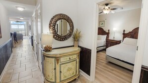 A hotel room with a bed, a dresser, a mirror, and a view of the hallway. - Coastal Comfort: 2BR Condo w/ Kitchen and Balcony (North Myrtle Beach)