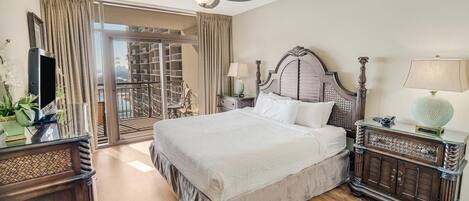 Une chambre d’hôtel avec un grand lit, un ventilateur de plafond, une table de chevet, une lampe et une vue sur l’extérieur.