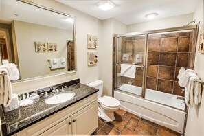 Une salle de bain dotée d’un meuble-lavabo à deux vasques, de toilettes, d’une douche à parois de verre et d’œuvres d’art décoratives murales.
