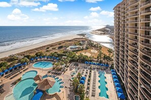 Un complexe hôtelier doté de plusieurs piscines, d’une plage et d’un immeuble de grande hauteur.