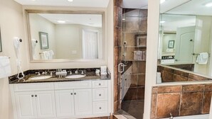 Une salle de bain moderne avec deux lavabos, un grand miroir, une cabine de douche et une baignoire.