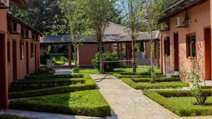 Un patio con sendero de piedra, setos cuidadosamente recortados y arquitectura tradicional.