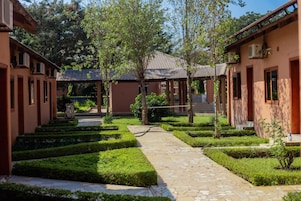 Un patio con sendero de piedra, setos cuidadosamente recortados y arquitectura tradicional.