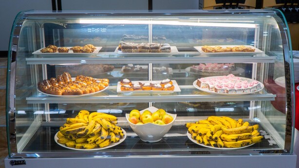 Una vitrina de panadería con distintos productos horneados y un bol de plátanos.