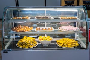 Una vitrina de panadería con distintos productos horneados y un bol de plátanos.