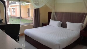 Habitación de hotel con cama, escritorio, silla y ventana con vistas al exterior.