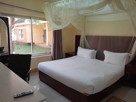 Habitación de hotel con cama, escritorio, silla y ventana con vistas al exterior.