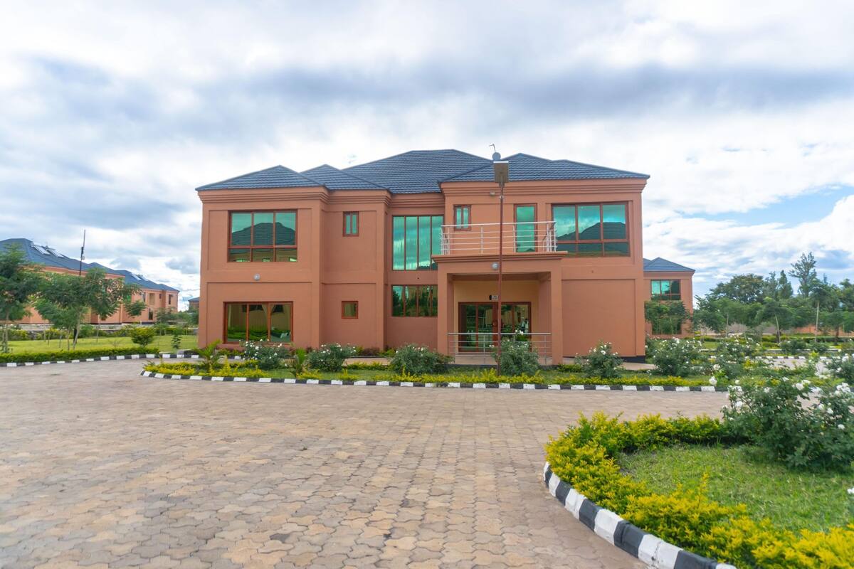 A two-story building with a flat roof, large windows, and a paved entrance area.