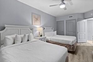 Ein Schlafzimmer mit zwei Betten, einem Deckenventilator und einem Nachttisch mit Lampe.
