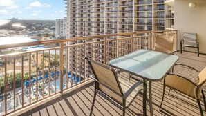 A balcony with a table and chairs, overlooking a pool and a beach. - Paradise Found: Oceanfront 3-Bedroom Condo (North Myrtle Beach)