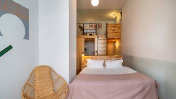 Un dormitorio con una cama, una silla de mimbre y un armario de madera.