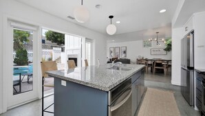 A modern kitchen with a large island, stainless steel appliances, and a dining area with a view of the outdoors.