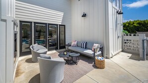 A covered patio with a sofa, chairs, and a small table.