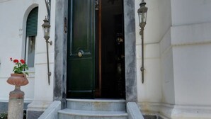 A set of stone steps leading to a green door with a decorative arch above.