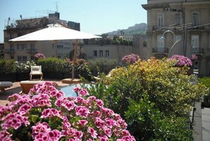 Um jardim no terraço com piscina, área de estar externa e plantas floridas.