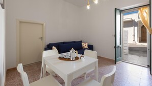 A room with a white table set for breakfast, a blue sofa, and a door leading outside. - 3732 Le Dimore del Sole - PT by Barbarhouse (Trepuzzi)