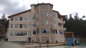 A multi-story building with a central tower, balconies, and a covered entrance. - Snow Touch Resort By Sriniwasa Hotels (Kullu)