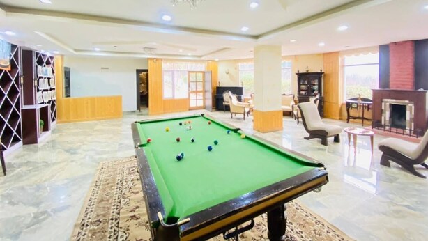 A spacious indoor area with a pool table, comfortable seating, and a fireplace. - Snow Touch Resort By Sriniwasa Hotels (Kullu)