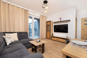 Relax in this stylish living room with a sofa, coffee table, and dining area, featuring a flat-screen TV and city views.