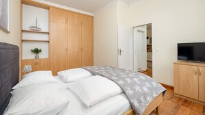 Une chambre à coucher avec un lit, une télévision, des meubles en bois et une petite plante.