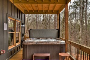Un bain à remous sur une terrasse en bois, avec vue sur une forêt.