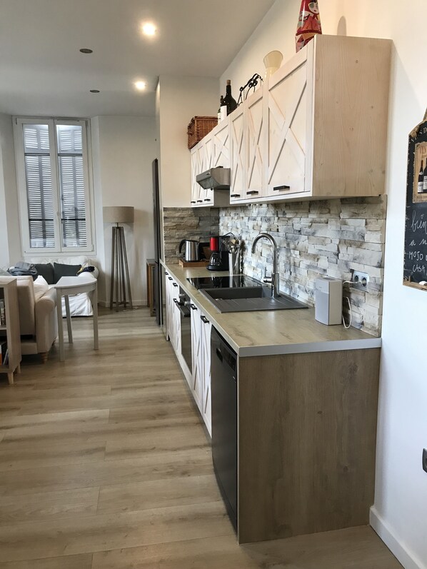 A modern kitchen with a central island, wooden cabinets, and a stone backsplash. - Beautiful apartment in Cannes (Cannes)