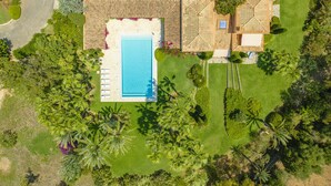 Vue aérienne d’une propriété dotée d’une piscine, de plusieurs bâtiments et d’un aménagement paysager luxuriant.