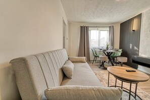 En moderne stue med en sofa, et rundt sofabord og et spiseområde med et bord og stole.