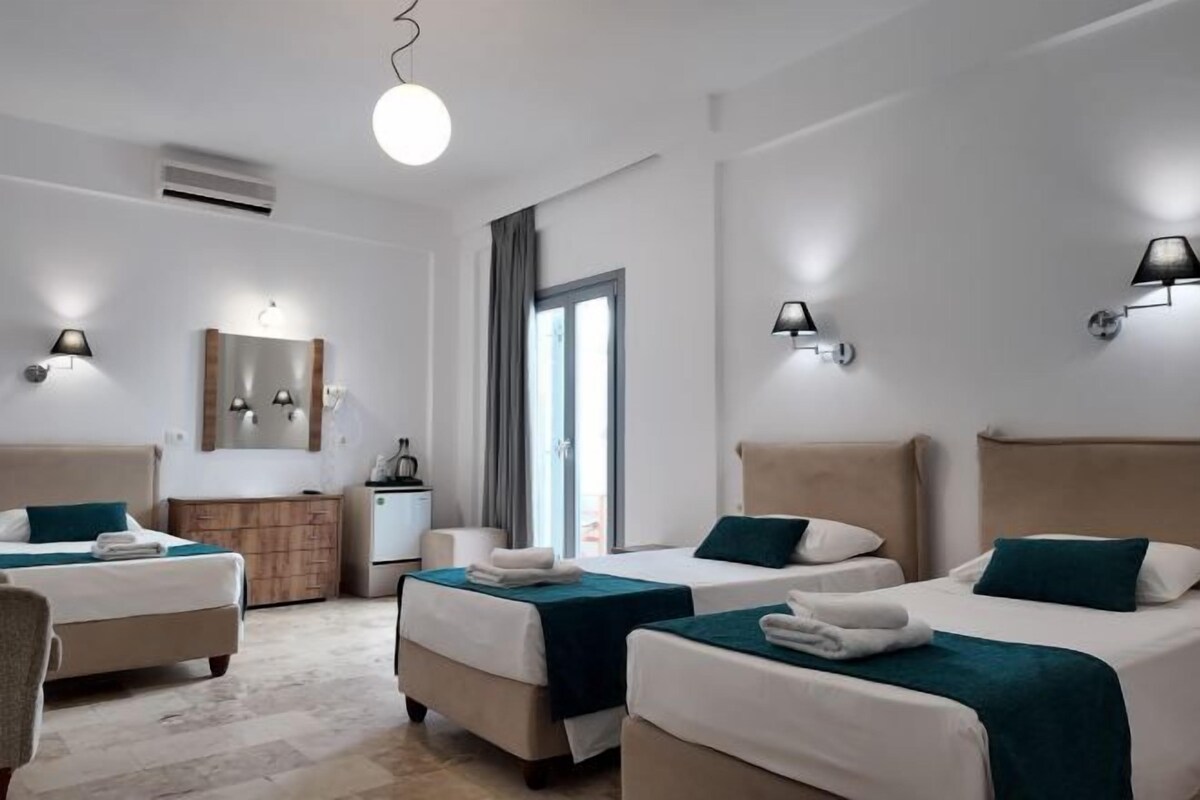 A hotel room with two beds, a mirror, a dresser, and a window with curtains.