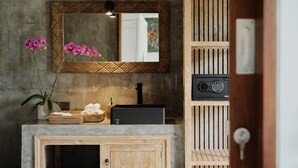 A bathroom with a wooden vanity, a mirror with a geometric frame, a black speaker, and a potted orchid. - Suarga Loka Ubud Villa (Ubud)