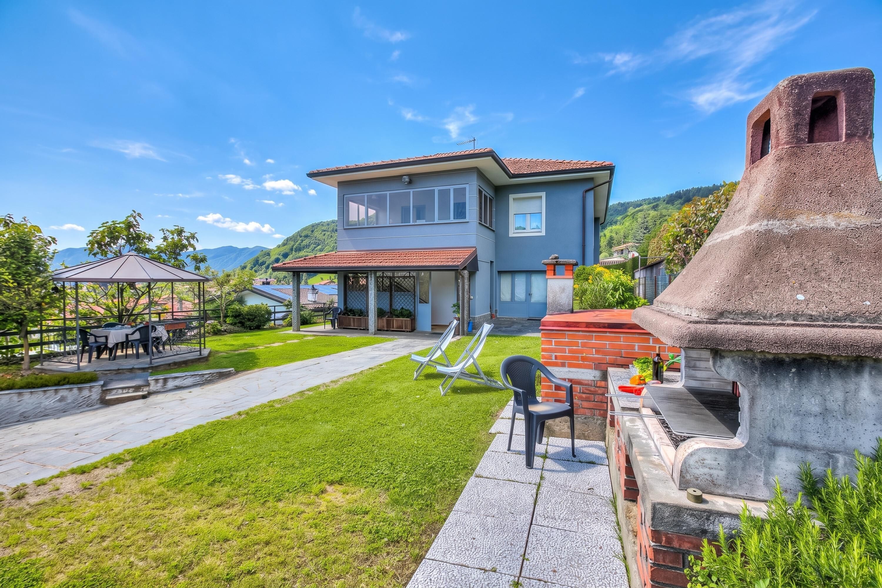A two-story house with a patio, outdoor seating, and a barbecue area.