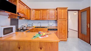 A kitchen with wooden cabinets, a microwave, stove, and a countertop with vegetables.
