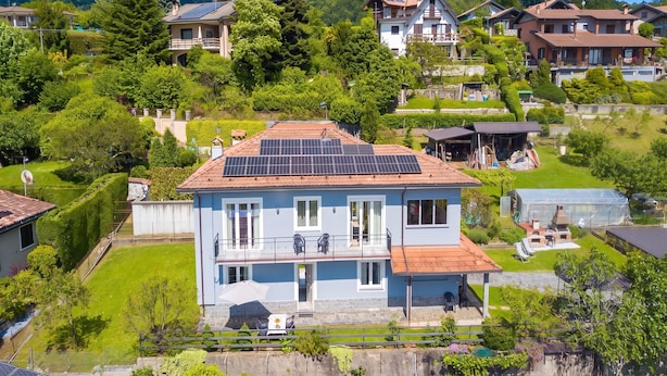 A residential building with a balcony, solar panels, and a garden.
