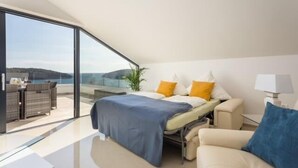Une chambre moderne comprenant un lit, un canapé, un bureau et une grande fenêtre donnant sur un paysage magnifique.