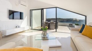 Un salon moderne avec une table basse en verre, un canapé et un téléviseur fixé au mur.